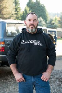 A man in black hoodie standing next to a truck.
