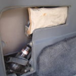 A car compartment with the door open and a bottle of water.