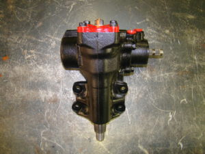 A black and red steering pump sitting on top of a floor.