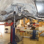 A car in the garage with its suspension lifted.