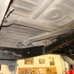 A car is under the ceiling of a garage.