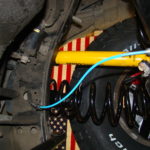 A blue wire is connected to the front suspension of an automobile.