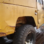 A close up of the side of an old yellow truck.