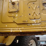 A close up of the side of an old yellow truck.