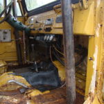 A yellow truck with the door open and some parts missing.