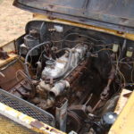 A yellow truck with the engine exposed.