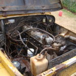 A truck with the engine exposed in an old car.