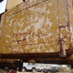 A large rusted box sitting on top of a metal structure.