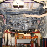 A car in the garage with its suspension lifted.