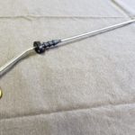 A metal rod with a yellow handle and black knob.